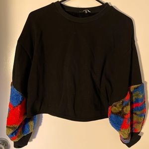 Black sweater with colorful arm cuffs.